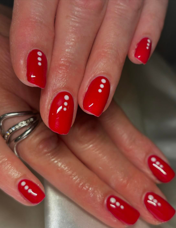 Red nails with white dots, decorated with silver rings on the fingers.