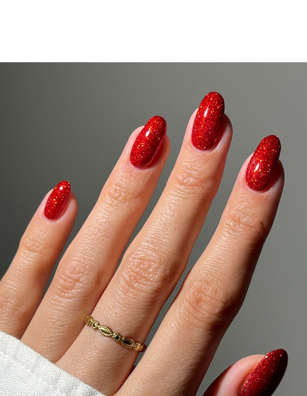 A hand with long, glittering red nails and a gold ring.