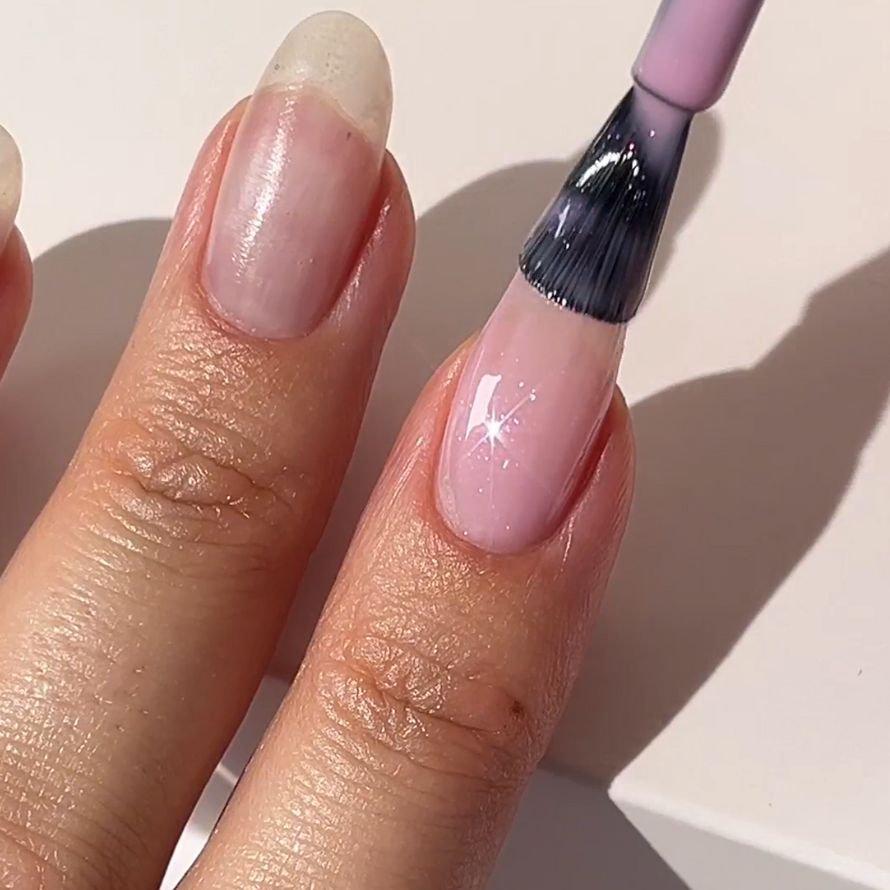 Finger is painted with glossy pink nail polish, captured in close-up.