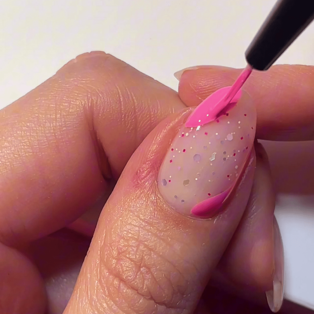 A hand with a glitter nail is decorated with pink nail polish.