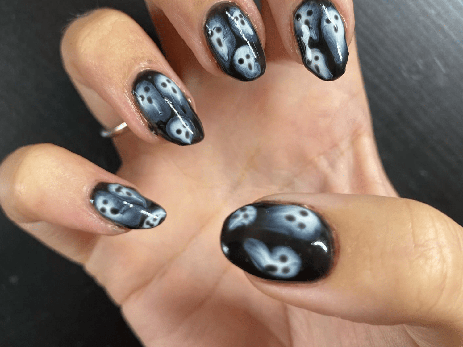 Hand with nails in black and white nail art with ghost motif.