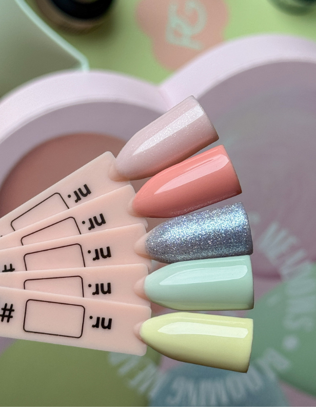 Five nail polish colors on swatches: light pink with shine, peach, silver glitter, pastel green and pastel yellow on a heart-shaped background.