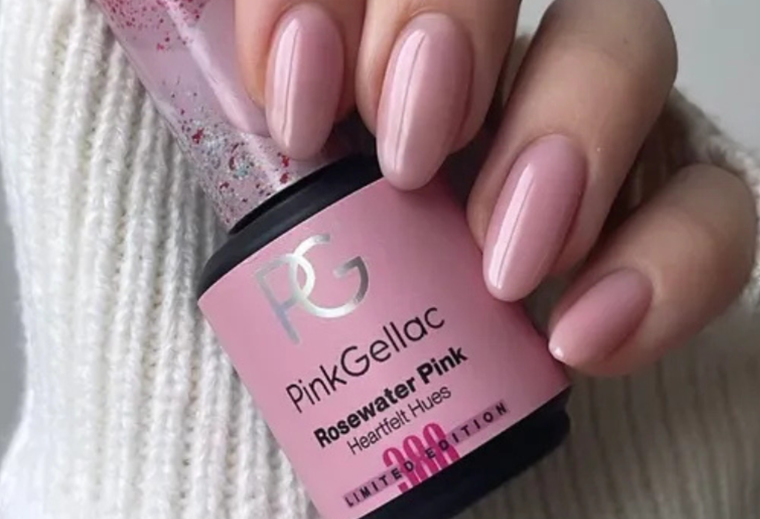 A hand with pink gel nail polish, holds a bottle of Pink Gellac in the color "Rosewater Pink" Limited Edition.