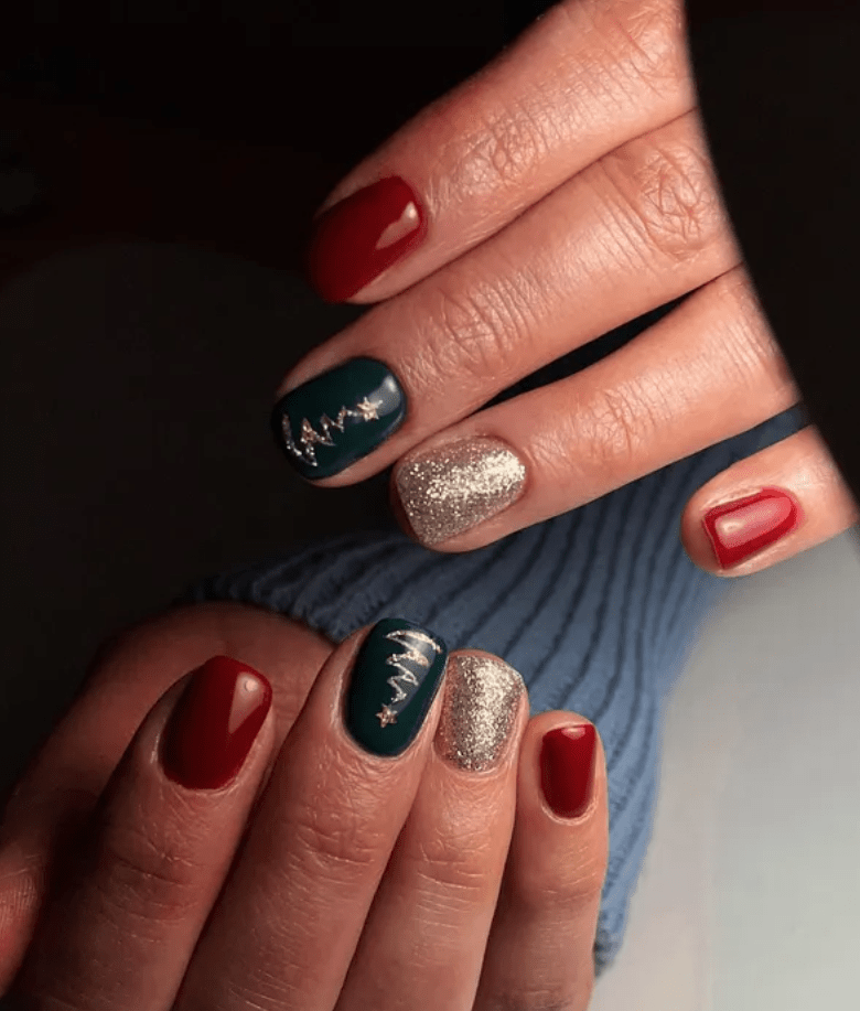 Hands with festive nail polish, including red, gold glitter and dark green nails with silver Christmas tree accent.