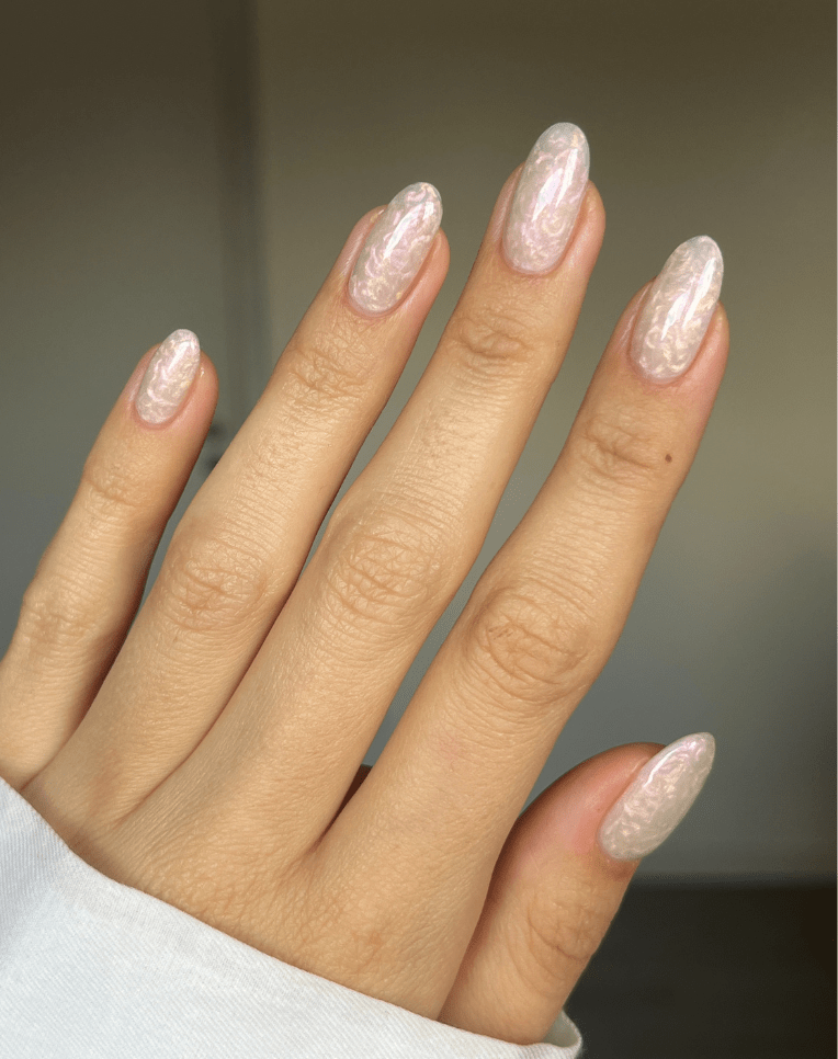 Hand with long, oval nails in a pearlescent pink shade.