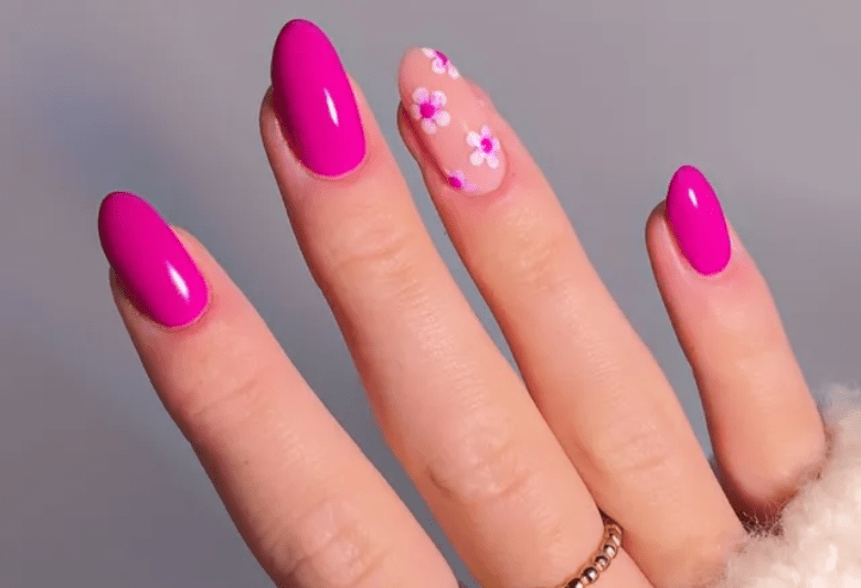 Bright pink nail polish on three fingers and a nail with a transparent base and colorful flowers.