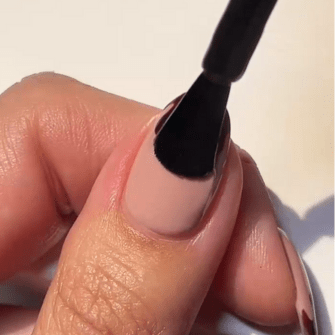 A hand that is busy applying black nail polish to a nail.