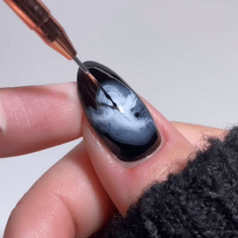 Black nail with white marble pattern, decorated with a fine brush on a finger.