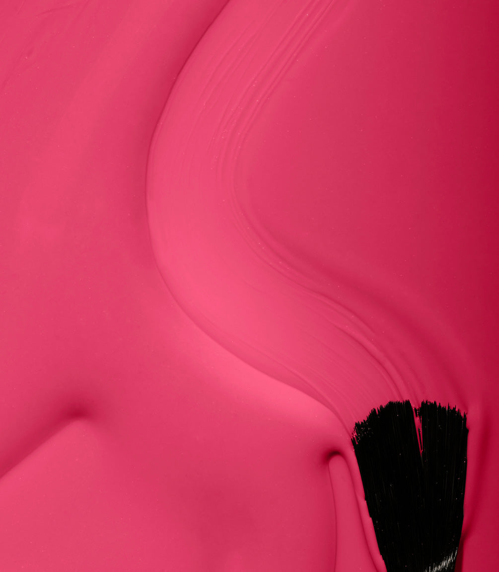 A close-up of a brush applying pink paint to a surface.
