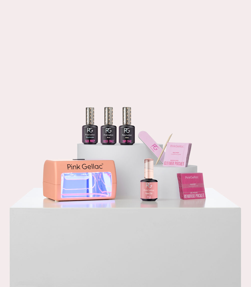 A collection of nail products on a white background, including a pink LED lamp from Pink Gellac, colorful nail polish bottles, a nail file, wooden stick, and bags with cleaner and remover.