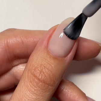 Nail is painted with a black nail polish brush. Hand with natural looking nail.