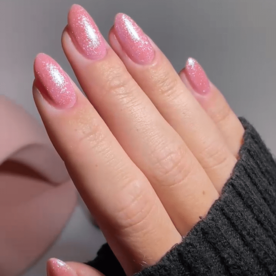 Pink shiny nails on a hand with black sweater.