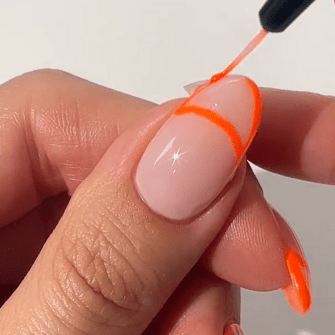 Hand paints bright orange nail polish on nails with a brush, against a white background.