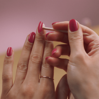 Two hands with pink nail polish, with one©©hand using a manicure stick on the other hand.