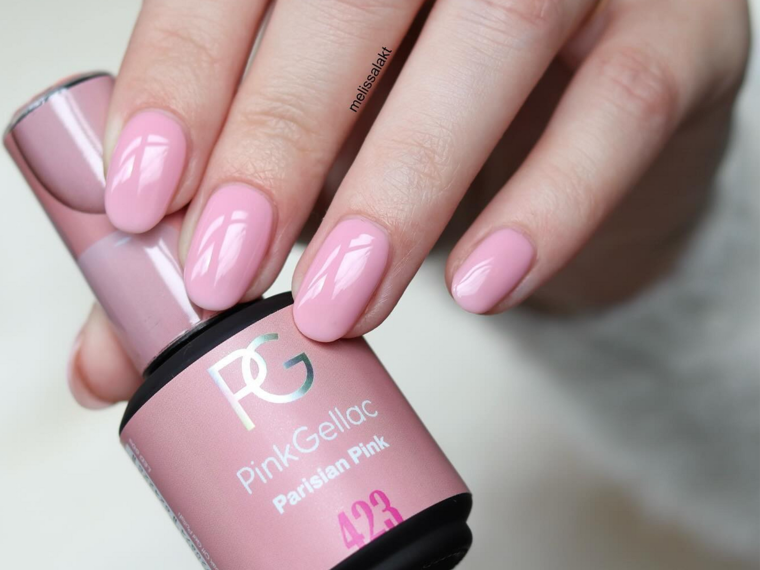 Pink gel nail polish applied on nails, bottle of Pink Gellac "Parisian Pink" number 423 in hand.