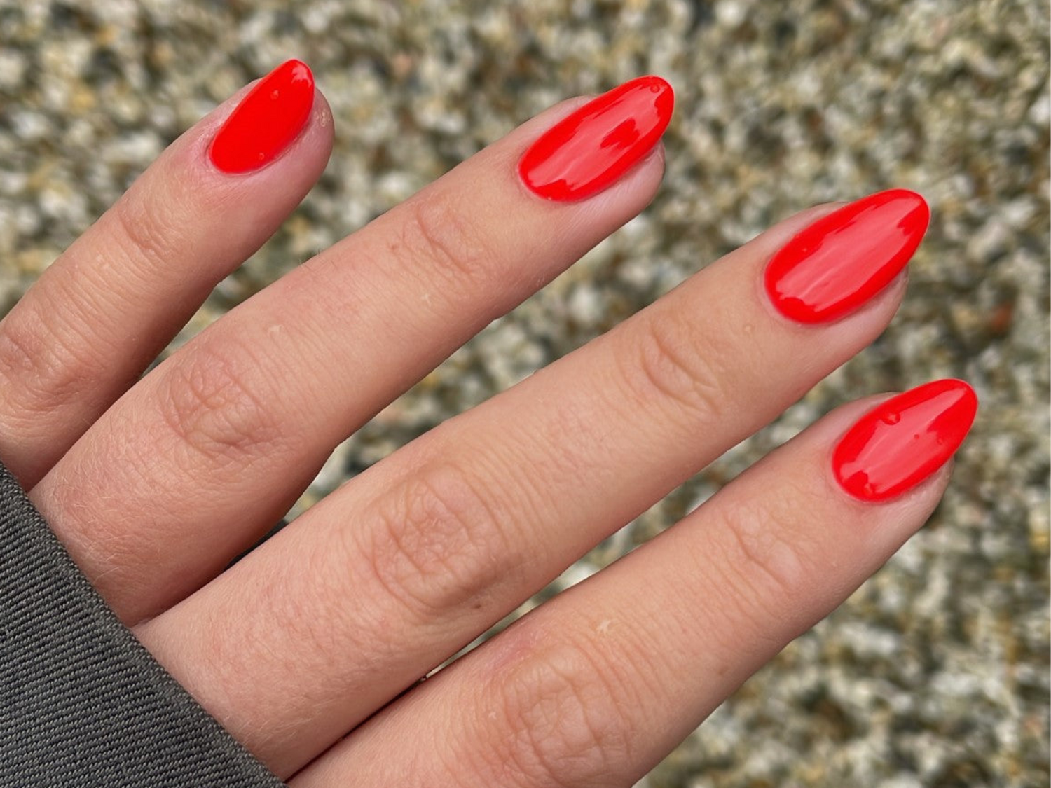 A hand with bright red, pointed nails against a blurred background.