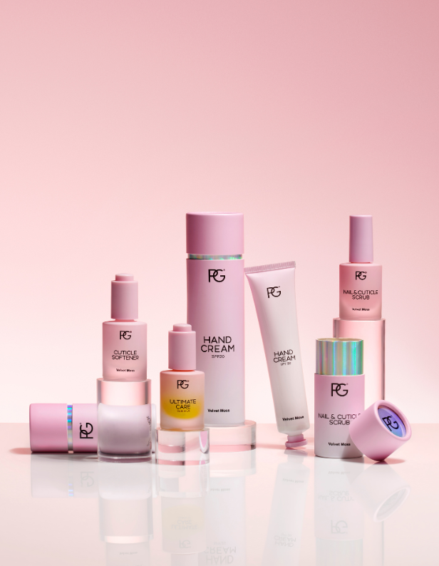 Pink and white bottles and tubes of skincare products against a pink background.