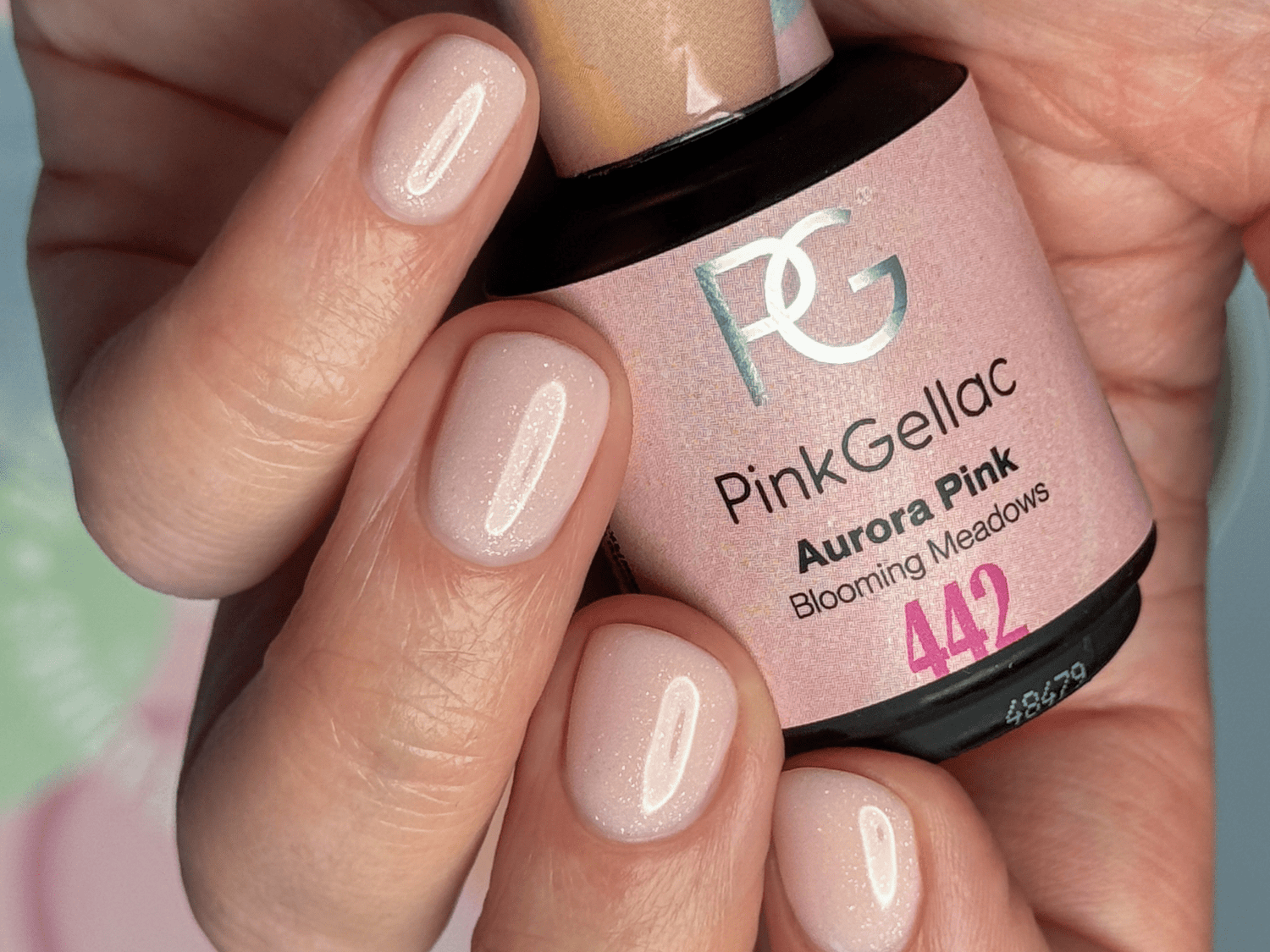 Pink gel nail polish on short, well-groomed nails with a bottle of Pink Gellac in the color "Aurora Pink" visible.