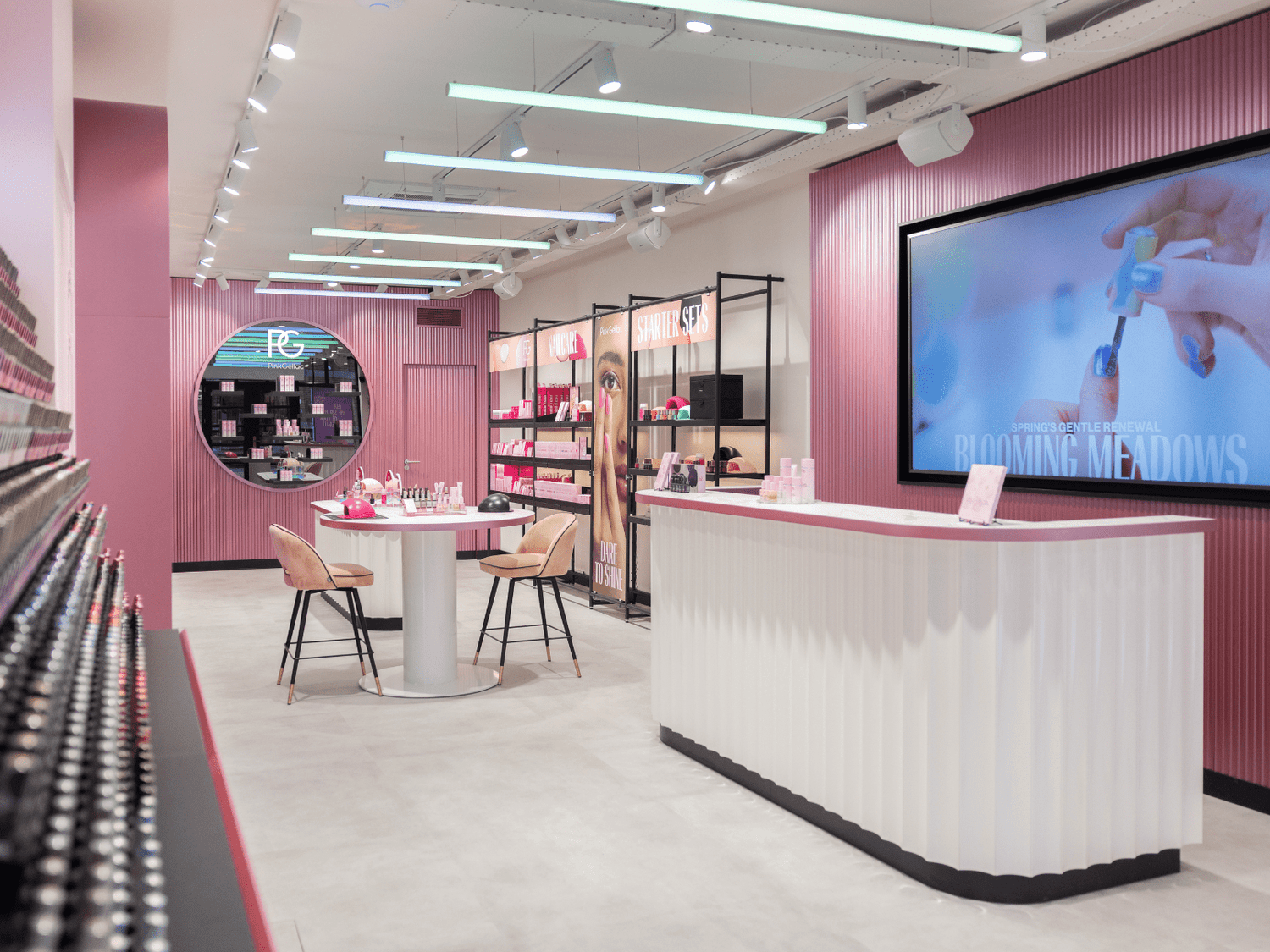 Luxurious beauty salon with pink tones, modern decor, product displays, round table and stylish chairs.