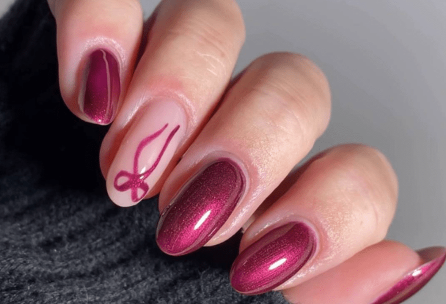 Close-up of a hand with burgundy nail polish and a decorative pattern on one©©nail.