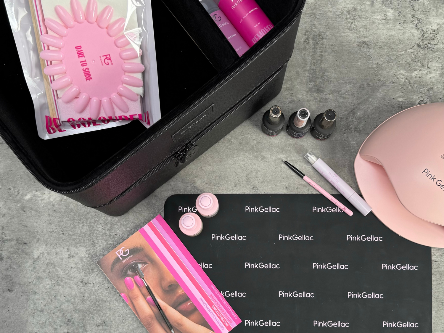 Nail styling set with gel polish, UV lamp, brushes and accessories from Pink Gellac on a gray background.