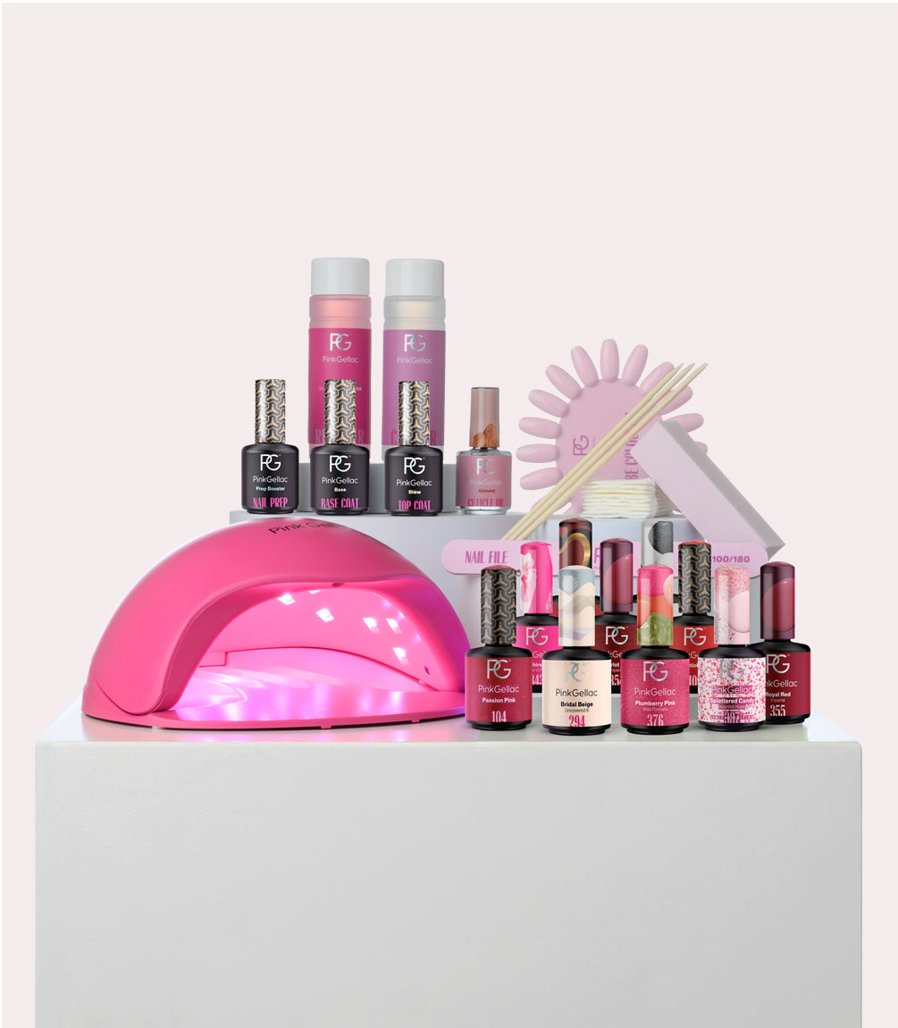 An extensive nail care package with gel nail polishes, a pink LED lamp, files, wooden sticks, and other manicure supplies.