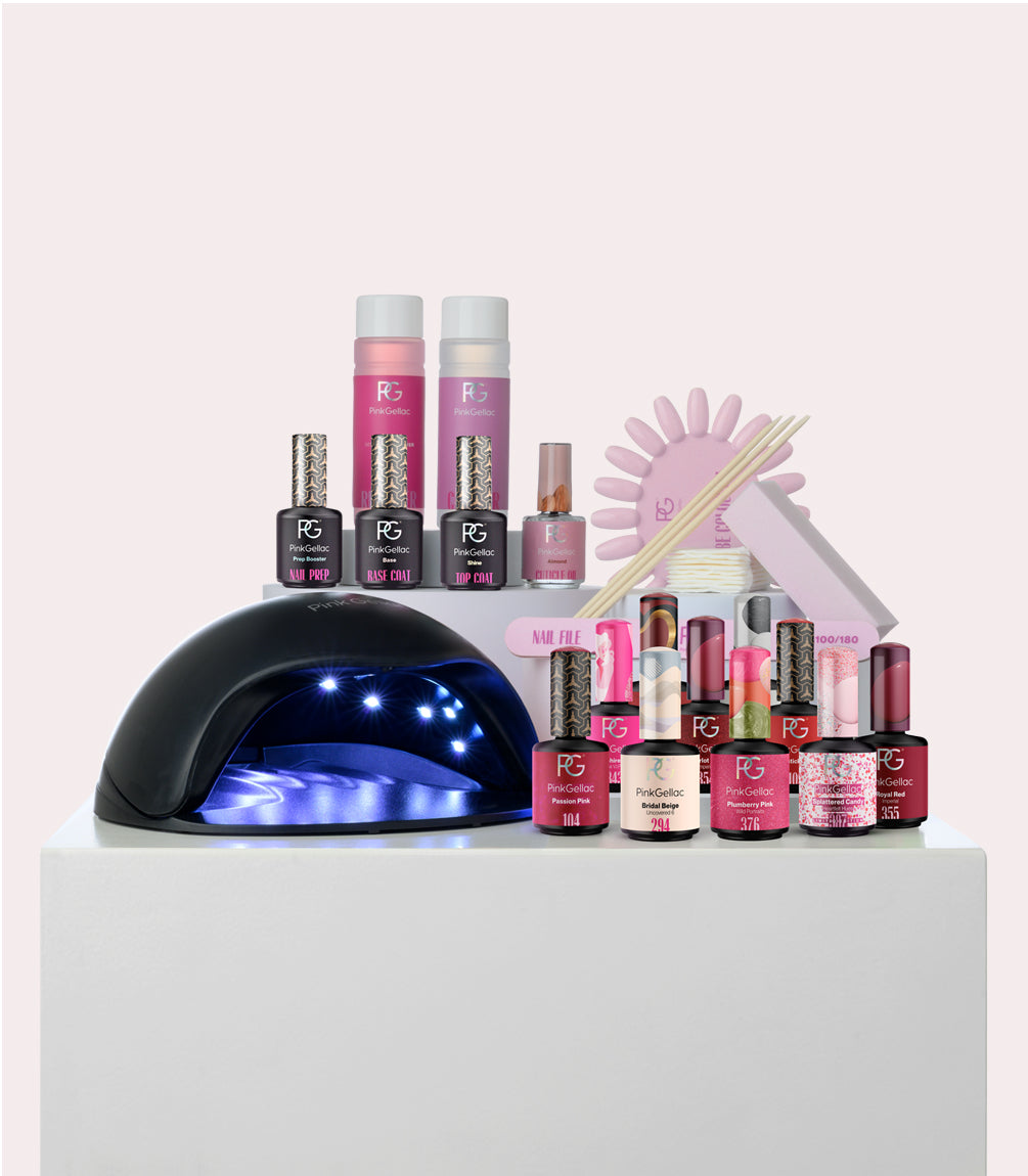 Nail care set with polishes, UV lamp, files and accessories on white background.