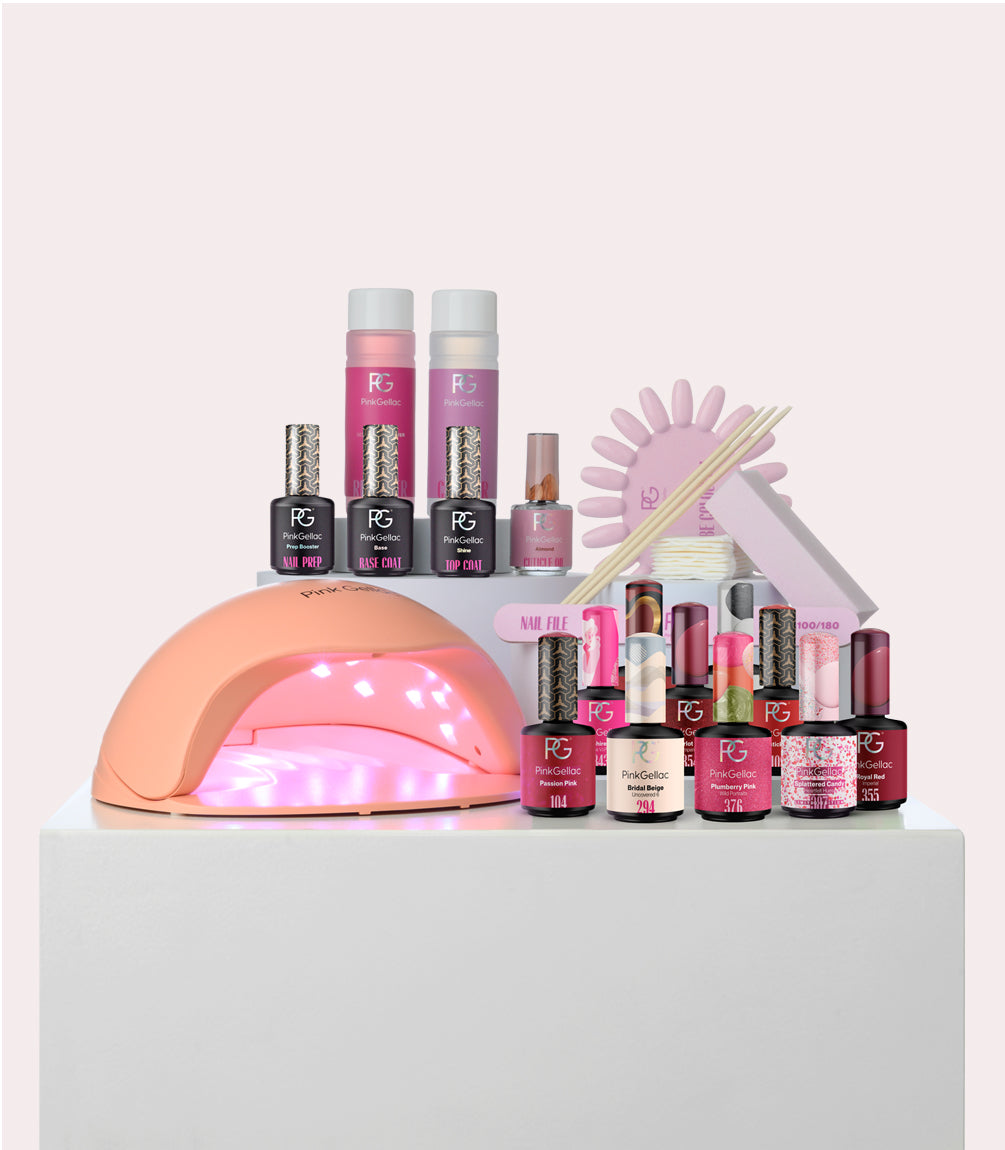A collection of nail care products, including an LED lamp, nail polish bottles, file set, and other manicure accessories, all organized on a white surface.
