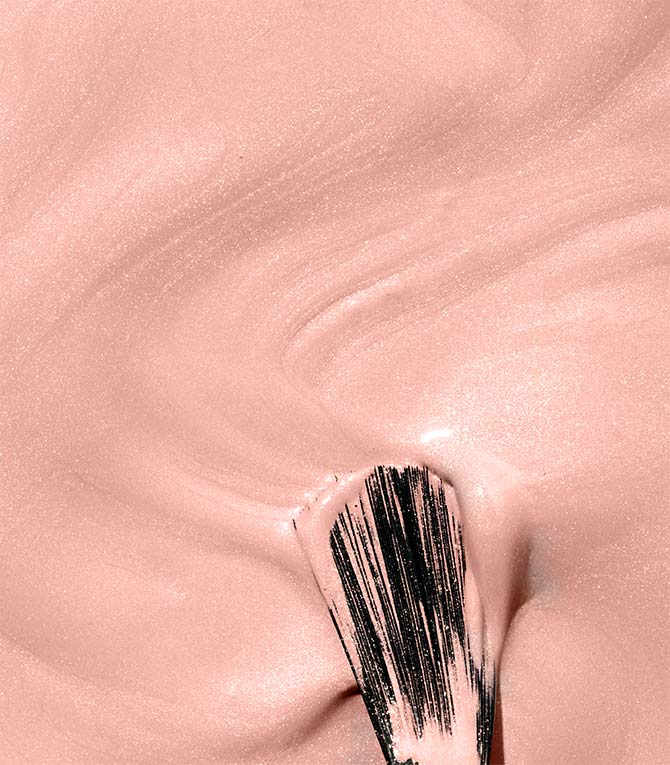 Makeup brush with pink cream on a pink background