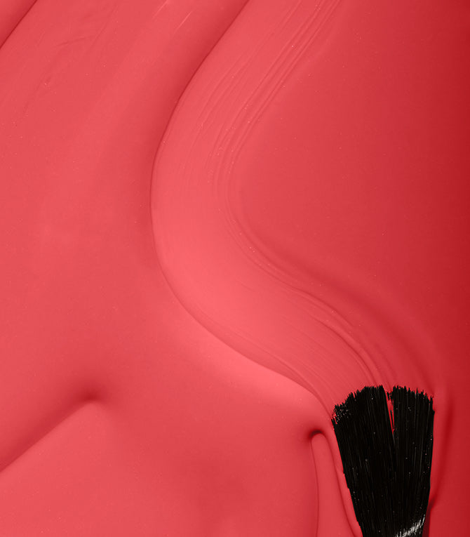 Close-up of a red lipstick with a black applicator on a red background