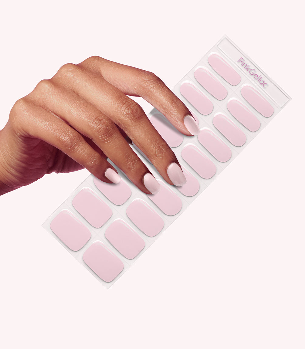 A hand holding a sheet of pink nail stickers.
