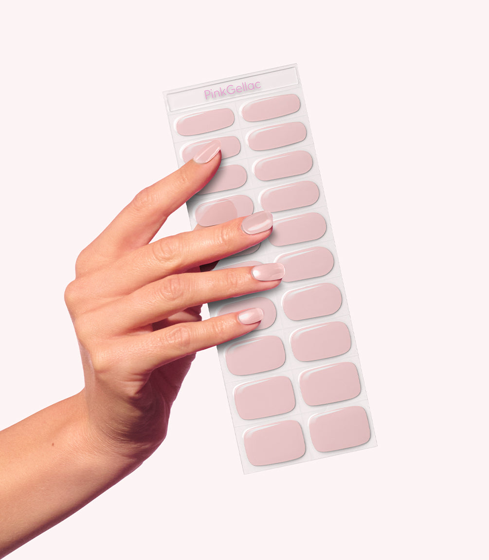 A hand holds a sheet of pink nail stickers.