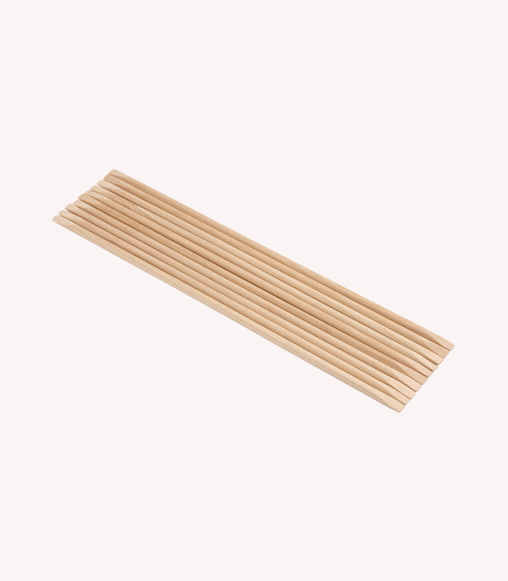 A row of twelve wooden chopsticks, lying parallel to each other, against a plain white background.