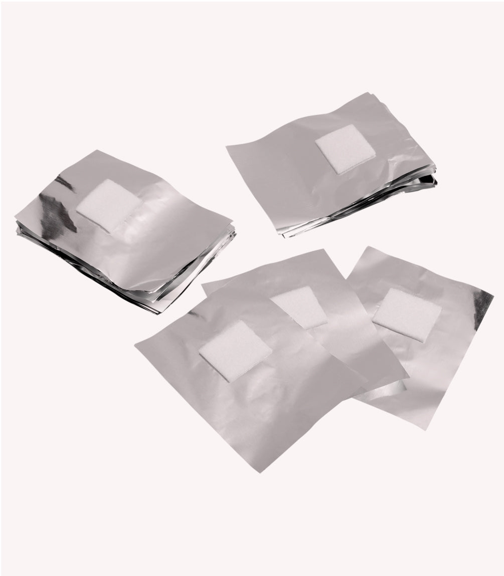 Four stacks of smooth aluminum foil sheets, each with a white square of foam in the middle, on a light background.