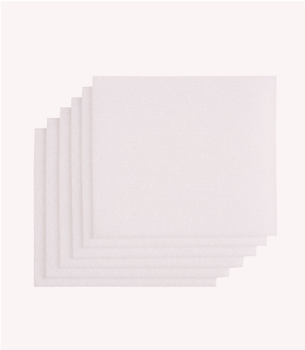 Six white napkins neatly stacked against a light gray background.