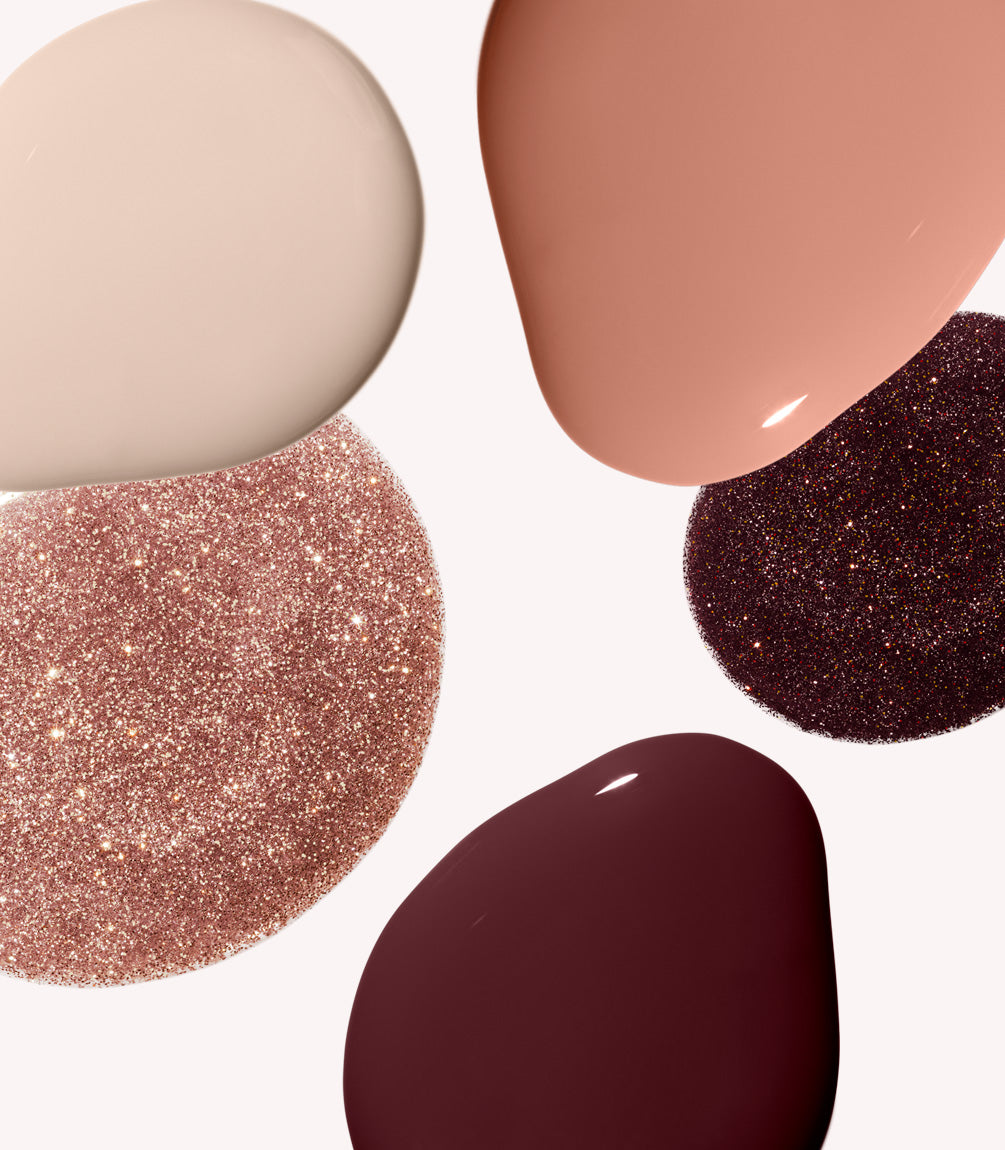 Different splashes of color and glitter textures of nail polish on a light background.