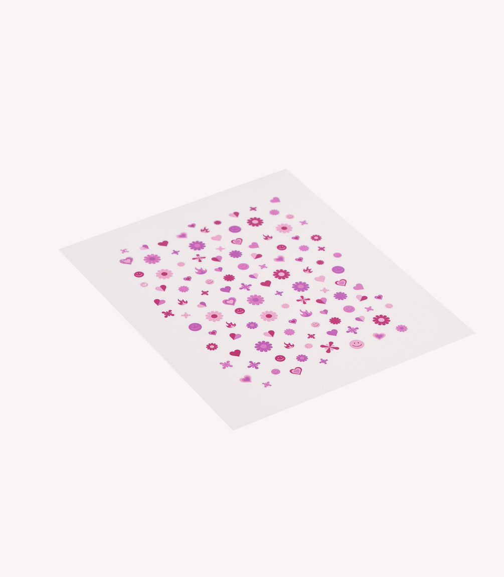 A sheet with small pink and purple stickers in the shape of flowers, hearts and other decorative symbols.