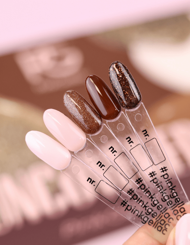 An image of five nail polish samples on plastic sticks, varying in colors from light pink to dark brown with glitter.