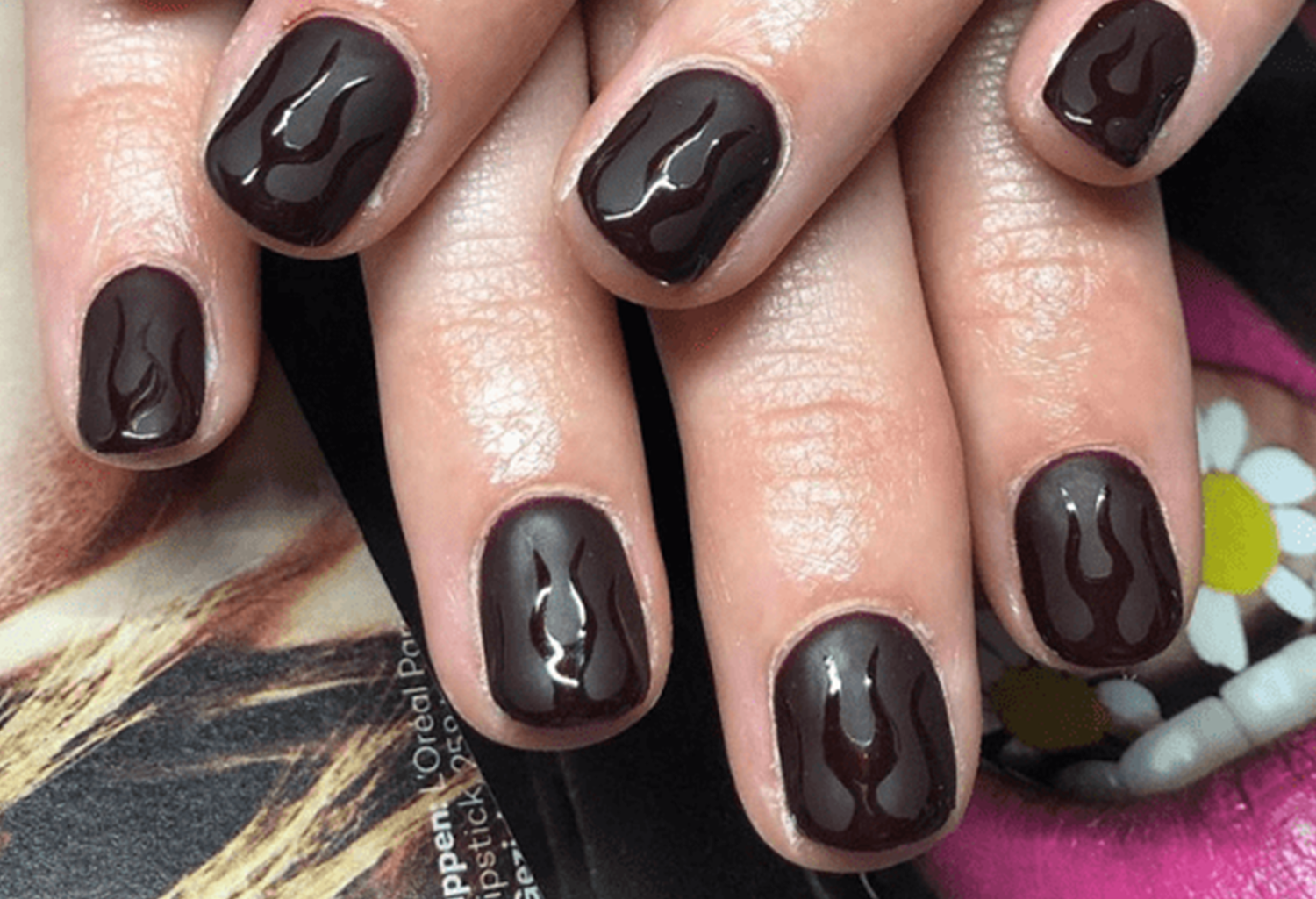 Dark brown nail polish with shiny flame pattern on short cut nails.