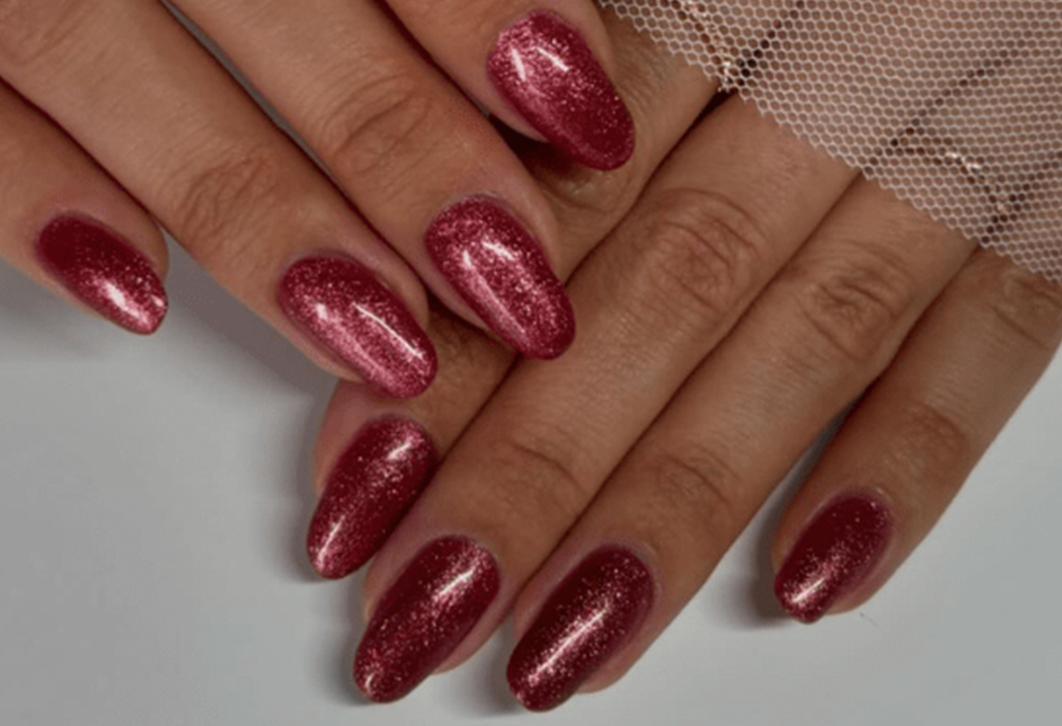 Hands with shiny dark red nail polish and a mesh detail.