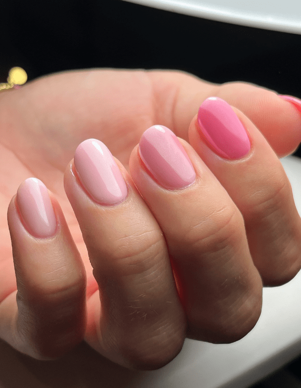 Five fingers with shiny pink nail polish in different shades, from light to dark pink.