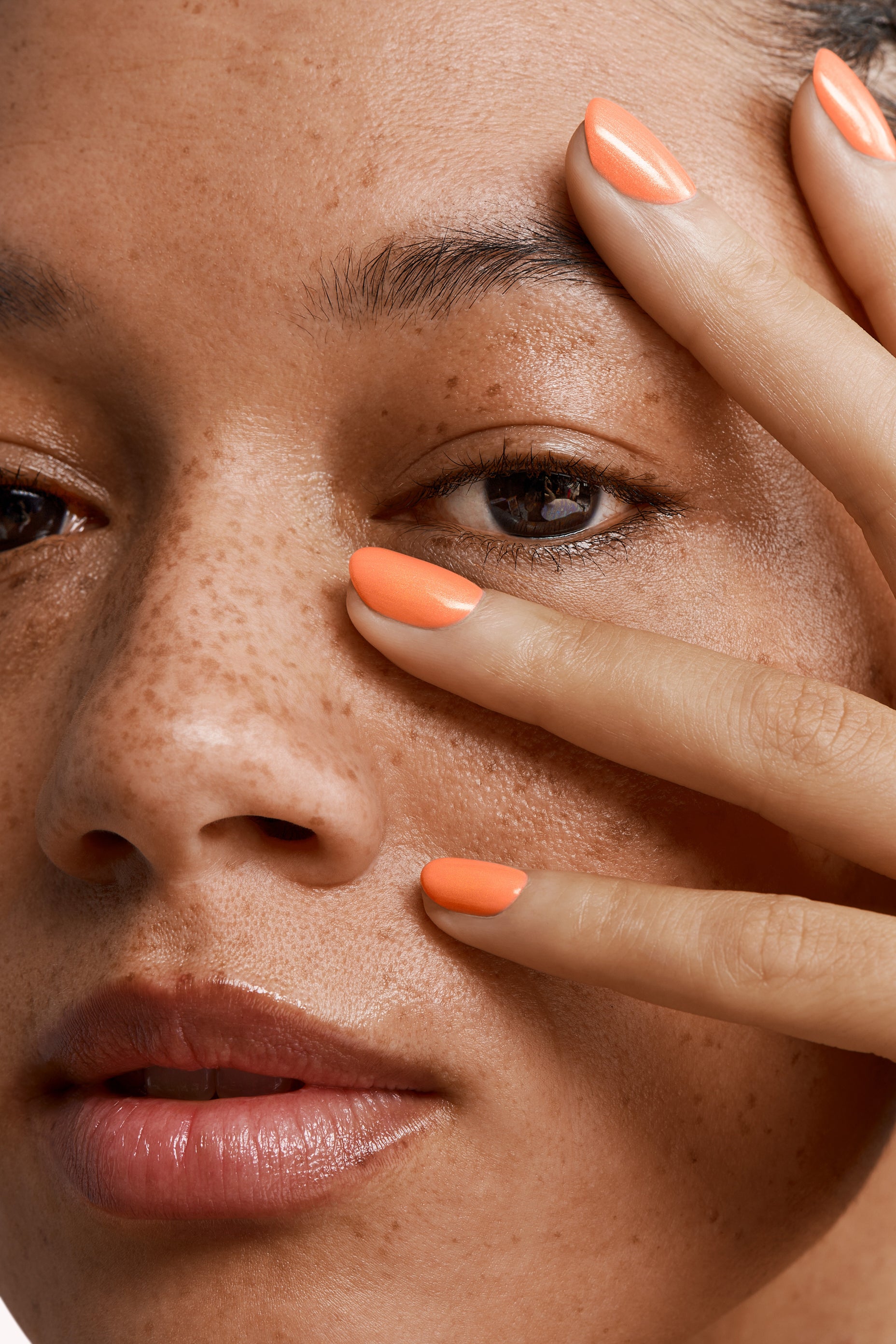 Close-up of a woman with Pink Gellac 159 Glamorous Peach manicured nails near her face.