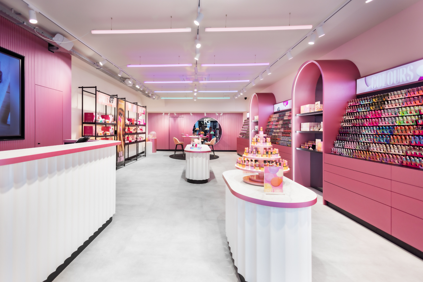 Interior of a modern, pink-and-white styled cosmetics store with displays of nail polish in different colors along the walls and a central island with products.