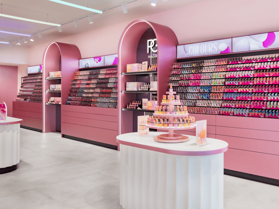 A well-organized retail space with pink walls and furniture, on which an extensive collection of colorful nail polish bottles can be seen, with a central display table with more nail polish products.
