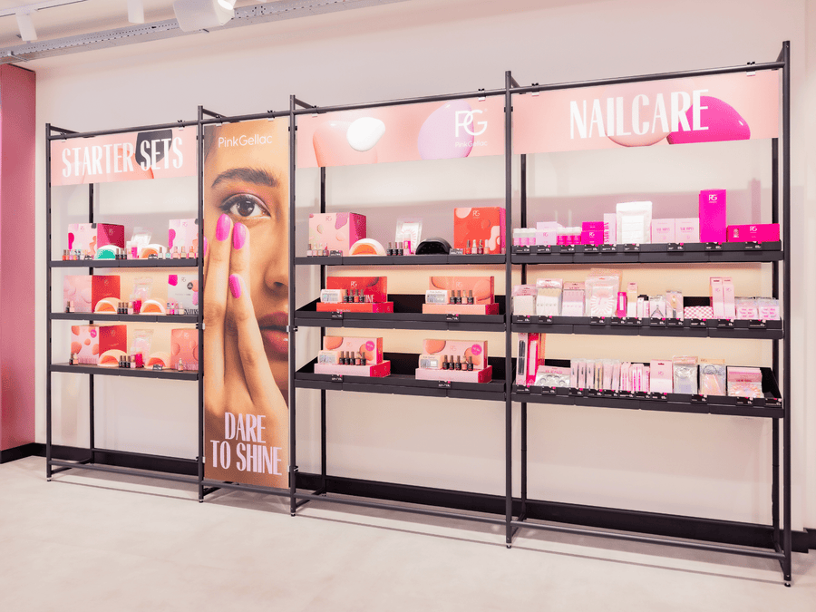 Store shelf with various nail care products and starter sets, with a large photo of a hand with pink nails and the text "Dare to Shine".