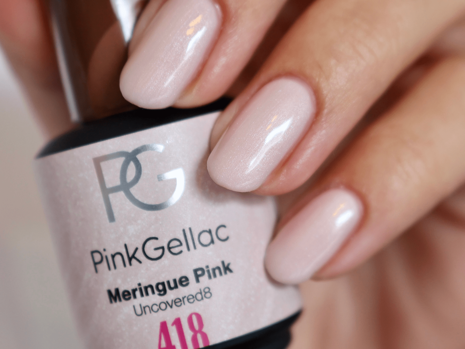 A hand with painted nails holds a bottle of Pink Gellac nail polish in the color Meringue Pink.