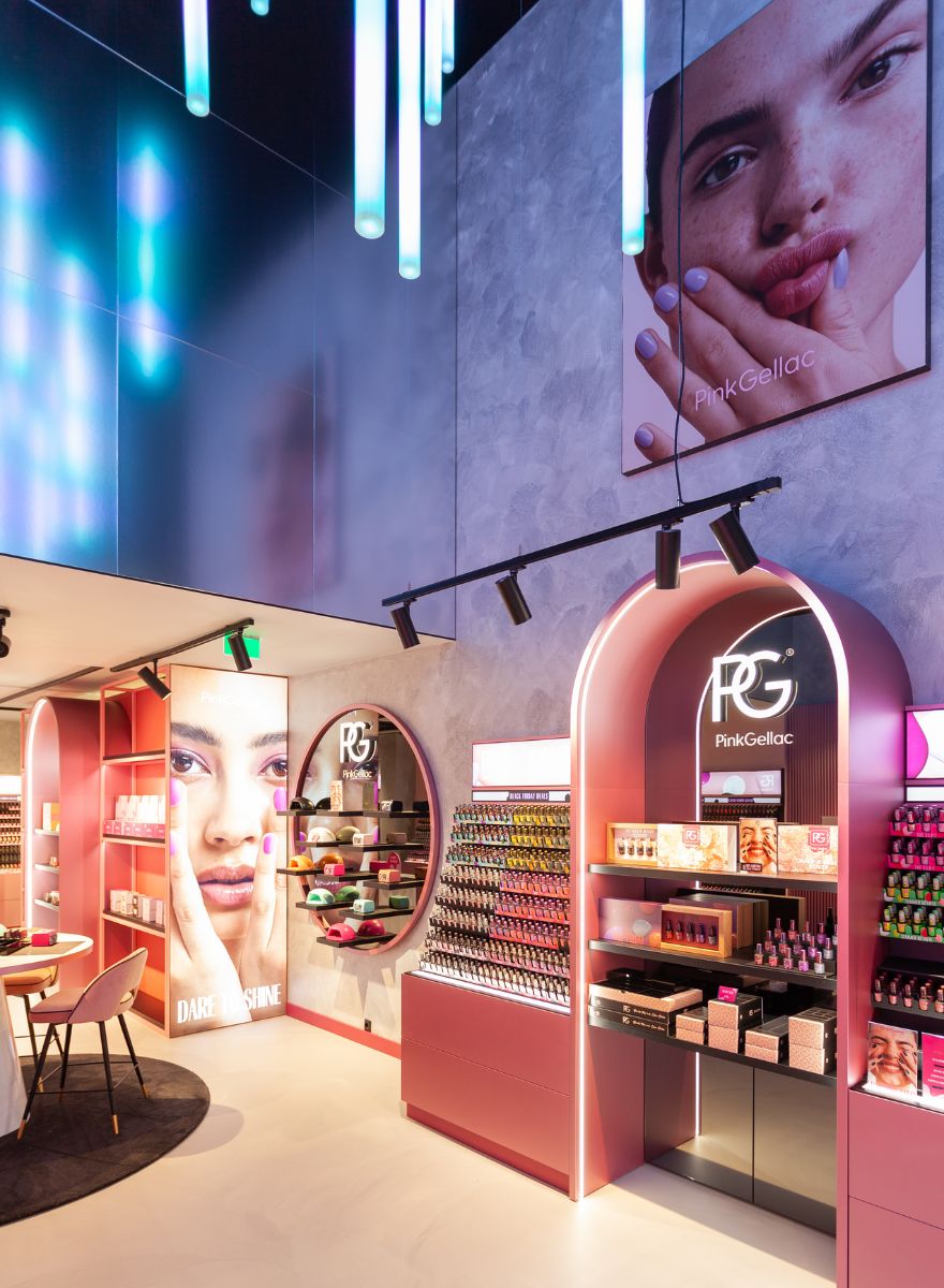 Interior of a colorful nail studio with pink and purple displays of Pink Gellac products, atmospheric lighting and large images of hands with painted nails.