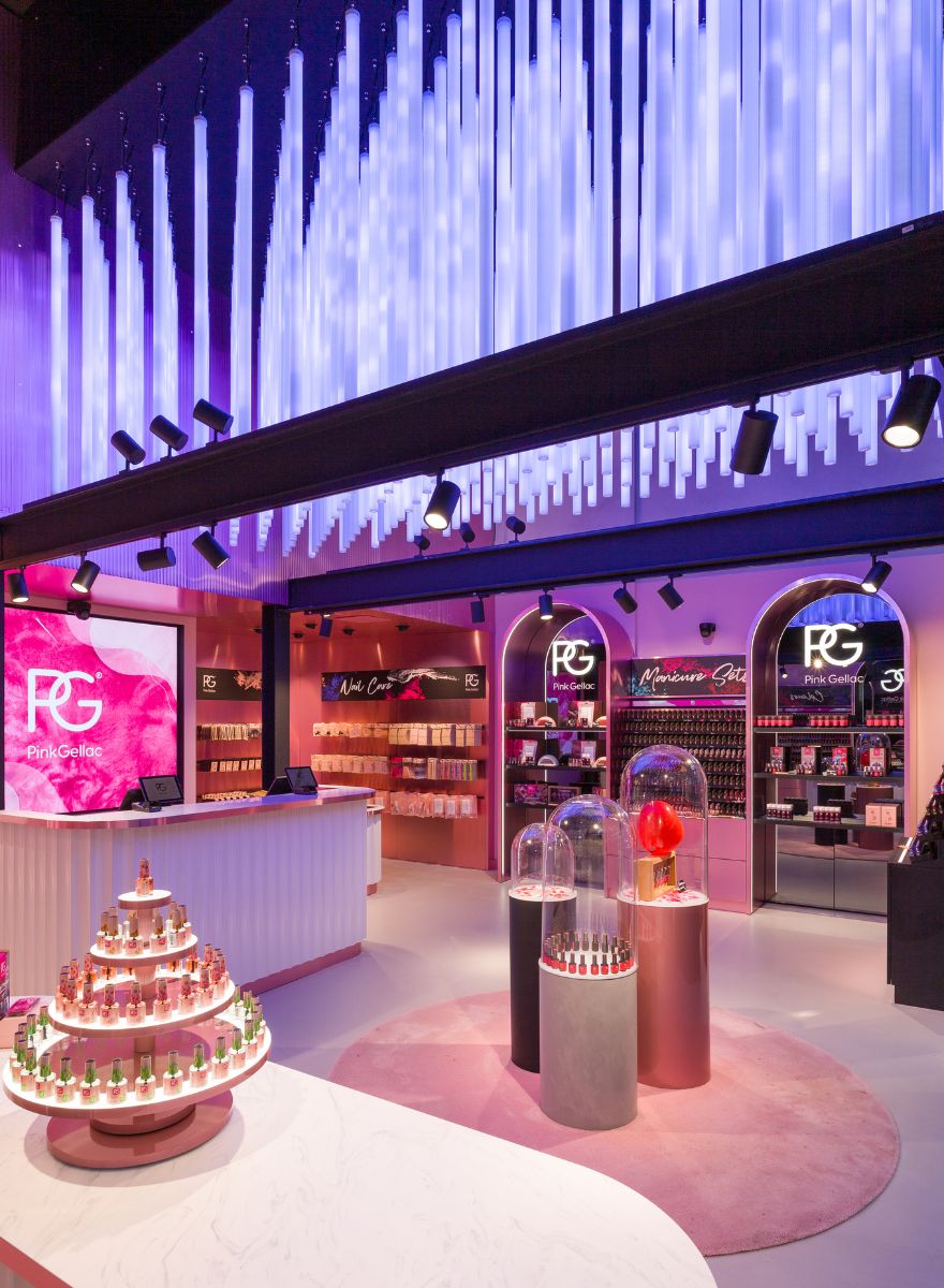 The image shows a colorful store interior with lighting on the ceiling, products displayed on tables and shelves, and the brand "Pink Gellac" prominently visible.