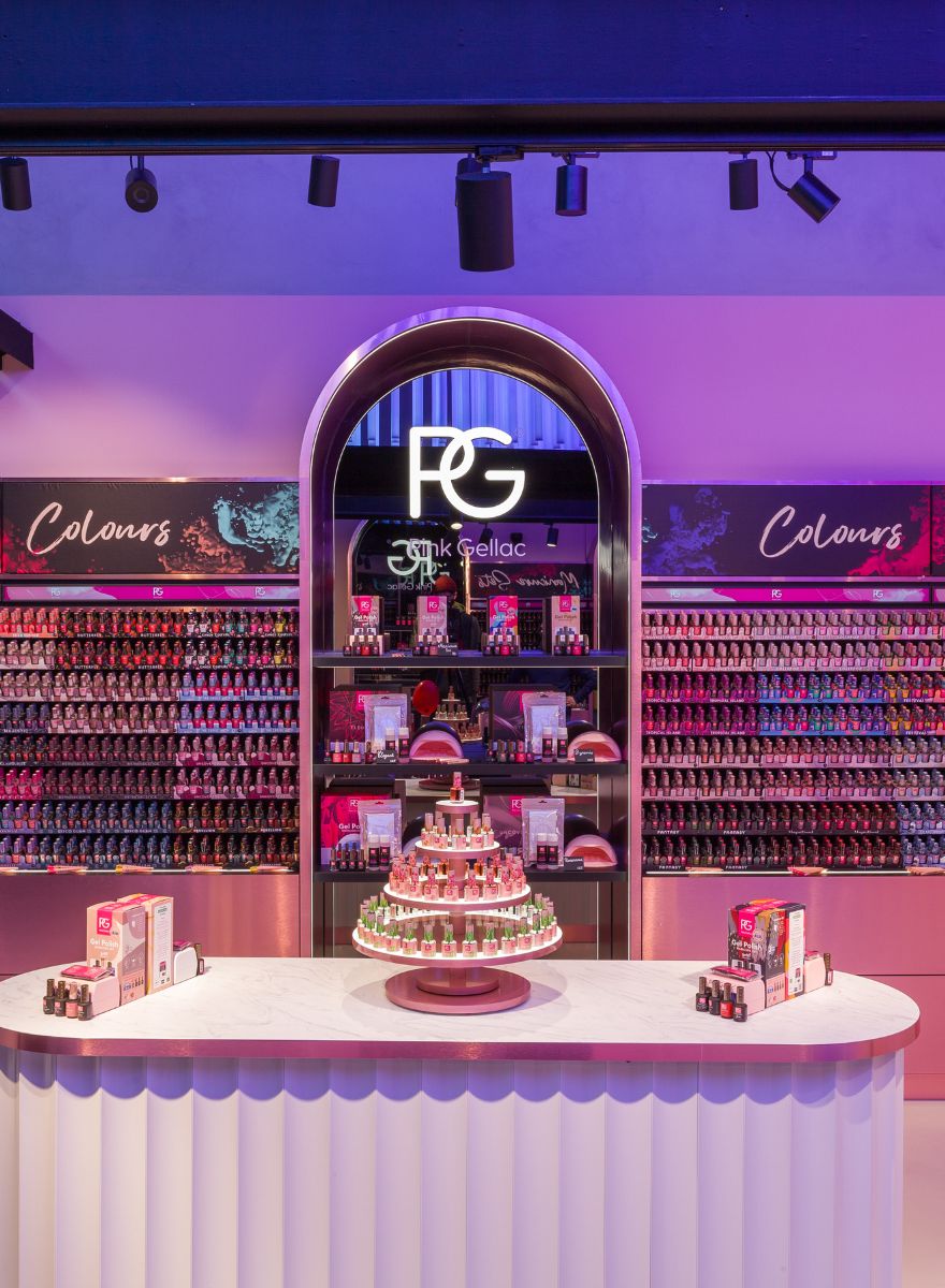 Interior of a nail polish shop with an illuminated display and multicolored gel nail polish bottles on a central table and shelves in the background.