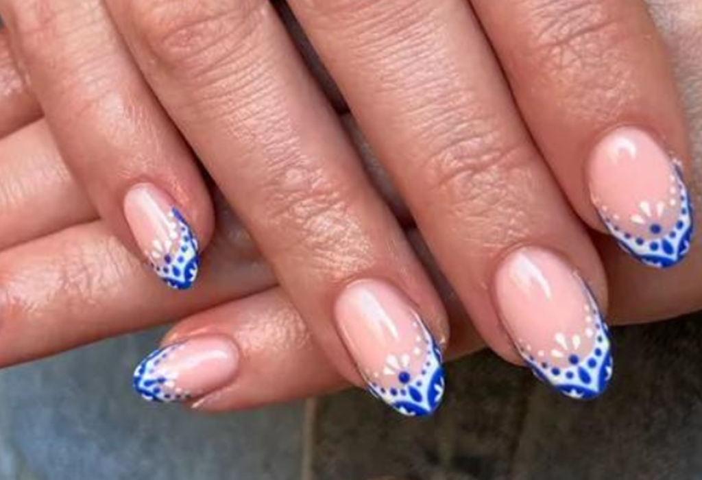 Nails with blue and white nail art on a natural pink base.